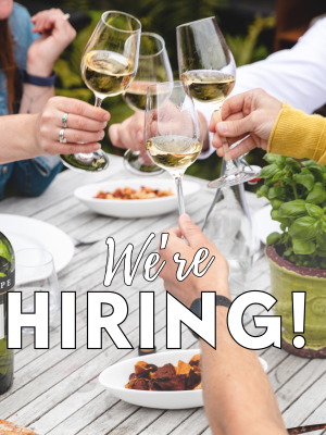 people clinking glasses with we're hiring text