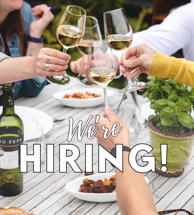people clinking glasses with we're hiring text